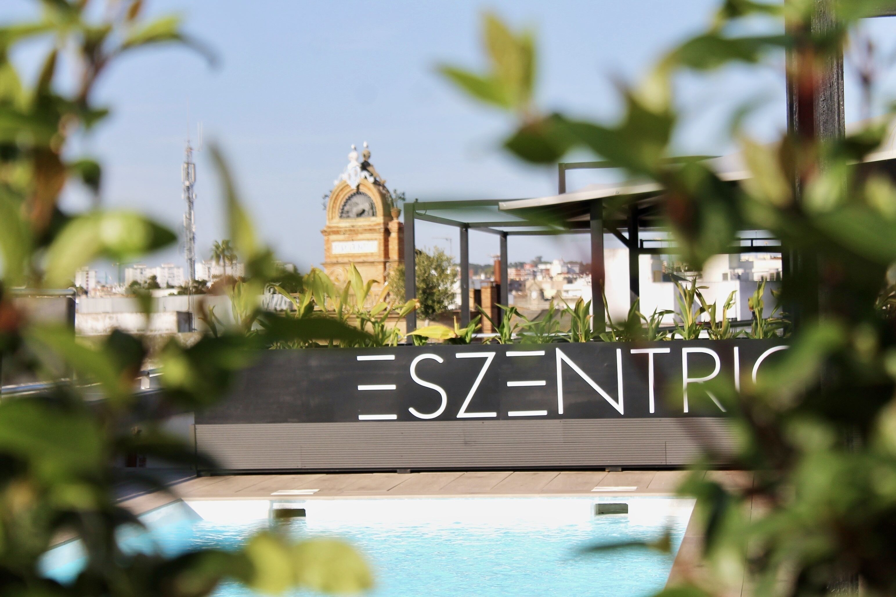 A pool area with a sign reading "ESZENTRIK" and a clock tower in the background.