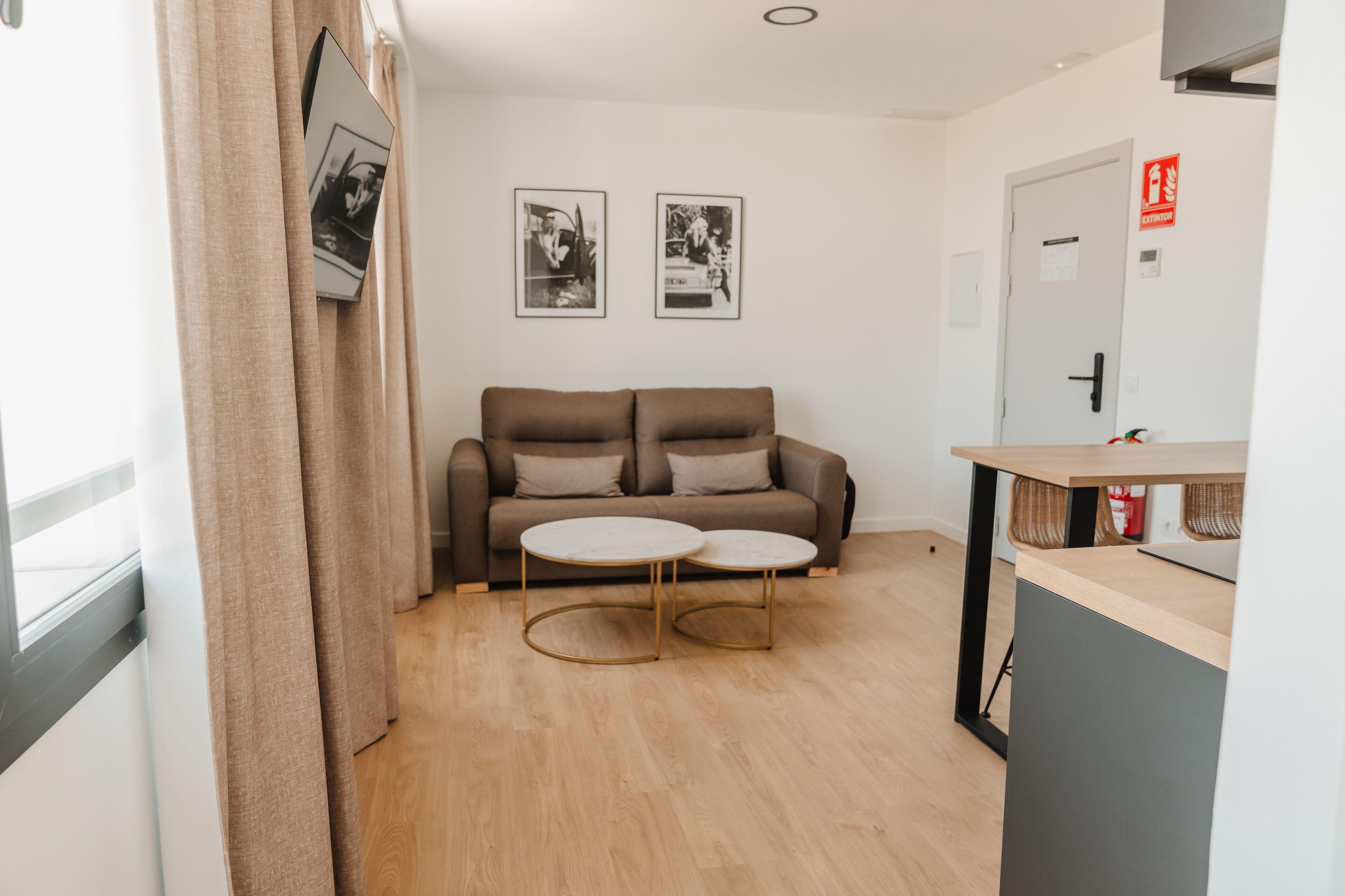 Ein modernes Wohnzimmer mit einer Couch, zwei runden Tischen und gerahmten Bildern an der Wand.