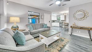A modern living room with a gray sectional sofa, a coffee table, and a ceiling fan.