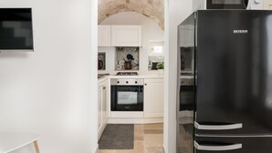 Une cuisine moderne avec des meubles blancs, un réfrigérateur noir et un four encastré.