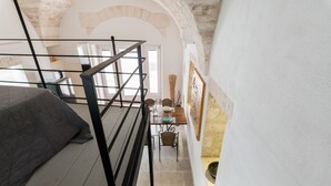 Un escalier mène à un coin repas où une table est dressée pour deux personnes, avec une chaise, et d’où l’on a vue sur la cuisine.