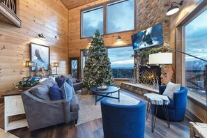 A cozy interior with a large Christmas tree, wooden walls, a fireplace, and a view through large windows. - Welcome to Eagle Summit National Park Lodge. Luxury Pool Cabin! (Sevierville)