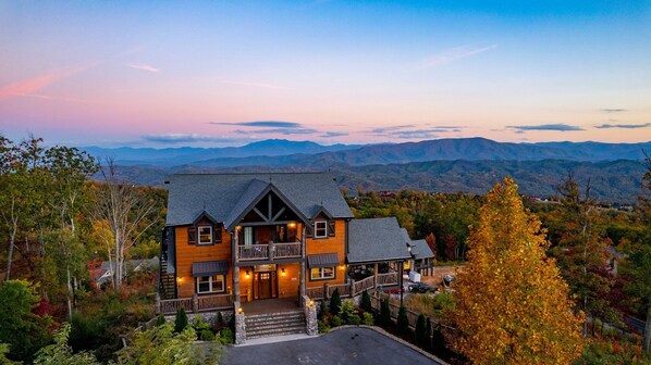 A large wooden house with a balcony, surrounded by autumn foliage and mountains in the background. - Welcome to Eagle Summit National Park Lodge. Luxury Pool Cabin! (Sevierville)