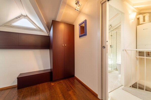 A room with a wooden wardrobe, a skylight, and a glass shower enclosure.