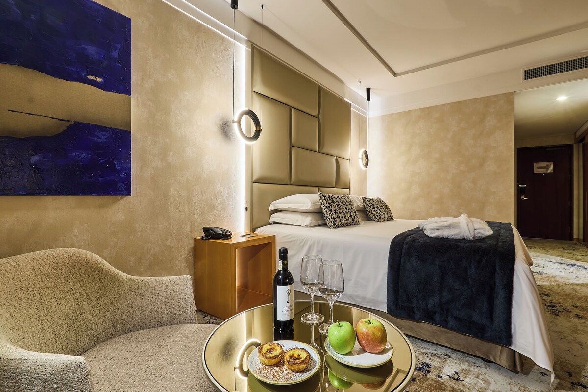 Ein Hotelzimmer mit Bett, Nachttisch und einer Sitzecke mit Sessel und Serviertisch.