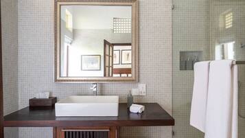A bathroom with a large mirror, a sink, and a shower.