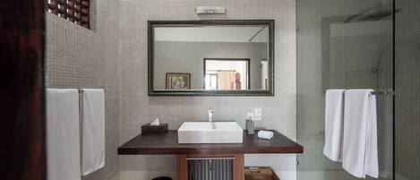 A modern bathroom with a large mirror, a white sink, and a glass shower enclosure.