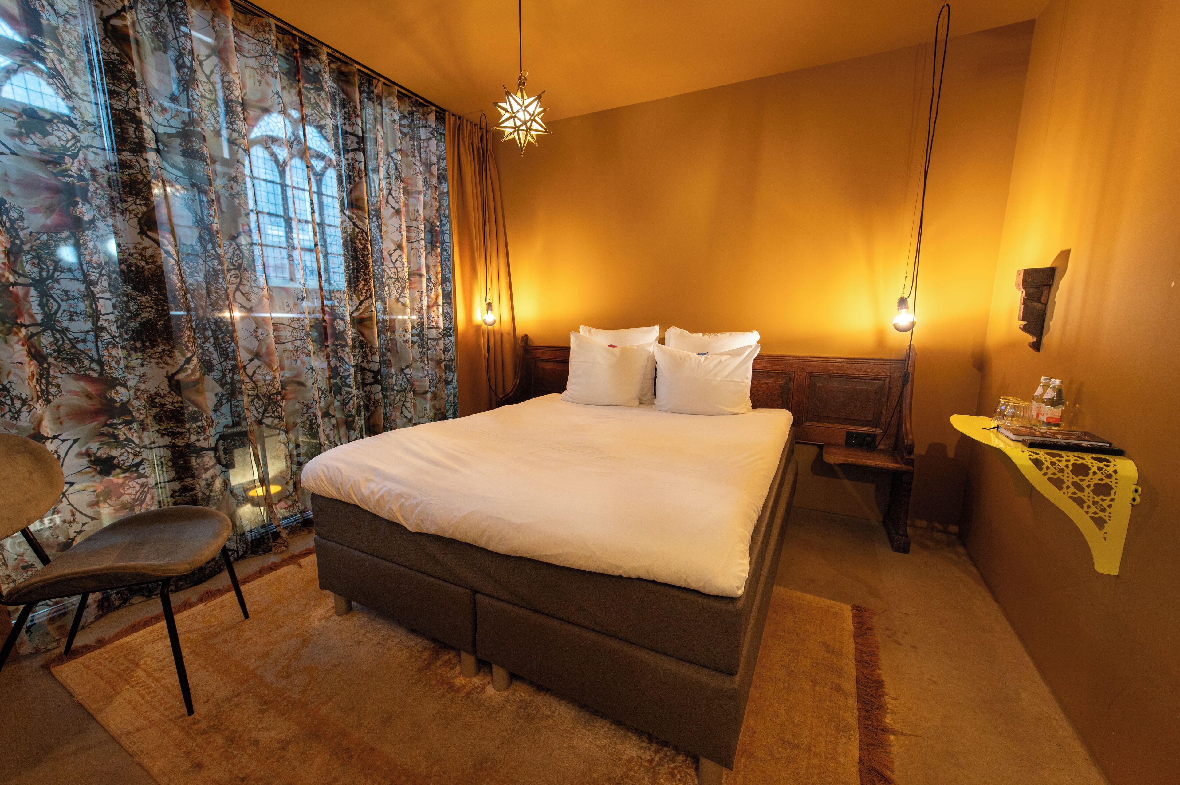Ein Schlafzimmer mit einem Bett, einem Sessel, einem Nachttisch und einem Beistelltisch.