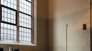 Ein Zimmer mit einem großen Bogenfenster, einem gelben Sofa, einem kleinen Holztisch und einem Holzboden mit einer integrierten Bank.