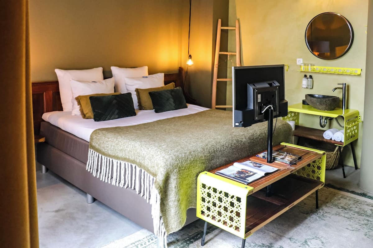 A neatly arranged bedroom with a bed, bedside table, and a small desk with a chair.