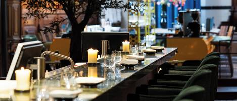 Un restaurante con una barra larga, velas y un centro de mesa con un árbol.