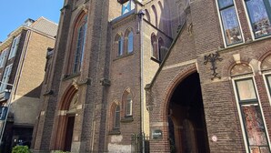 Eine historische Kirche mit einem markanten Turm, Bogenfenstern und einer Ziegel-Fassade.