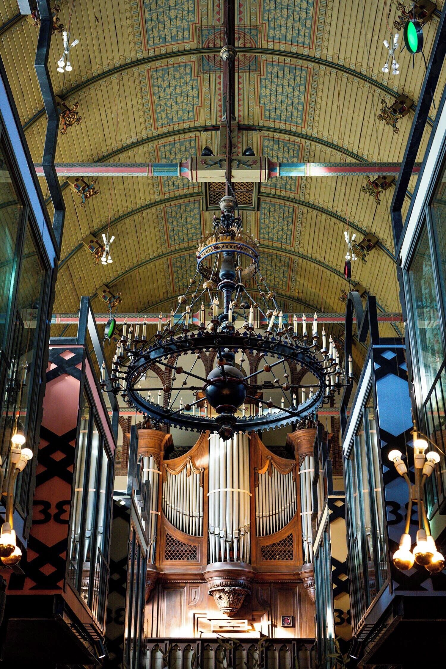 Een versierd orgel met ingewikkelde details en een grote kroonluchter erboven.