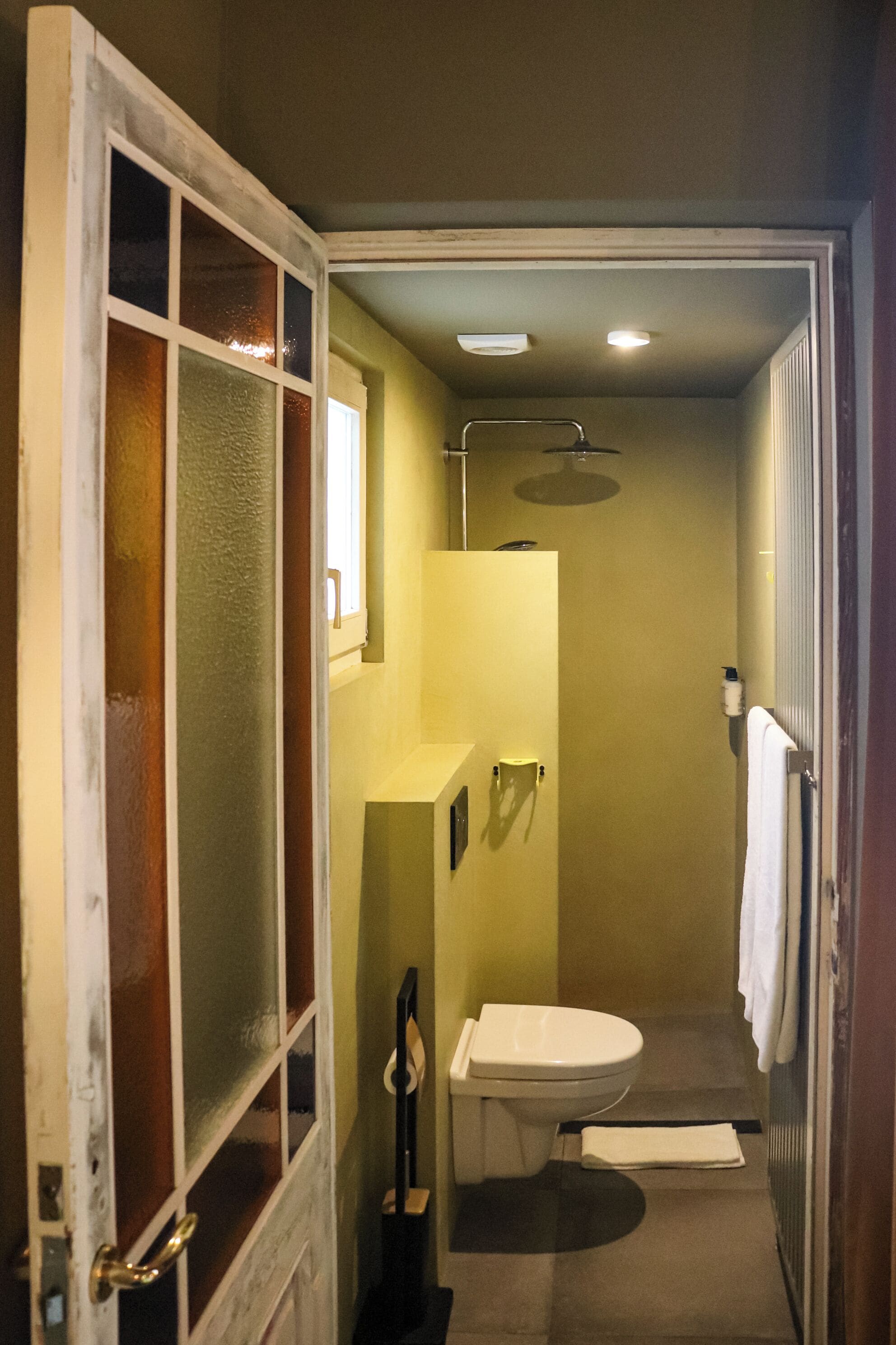A compact bathroom with a toilet, sink, and shower.