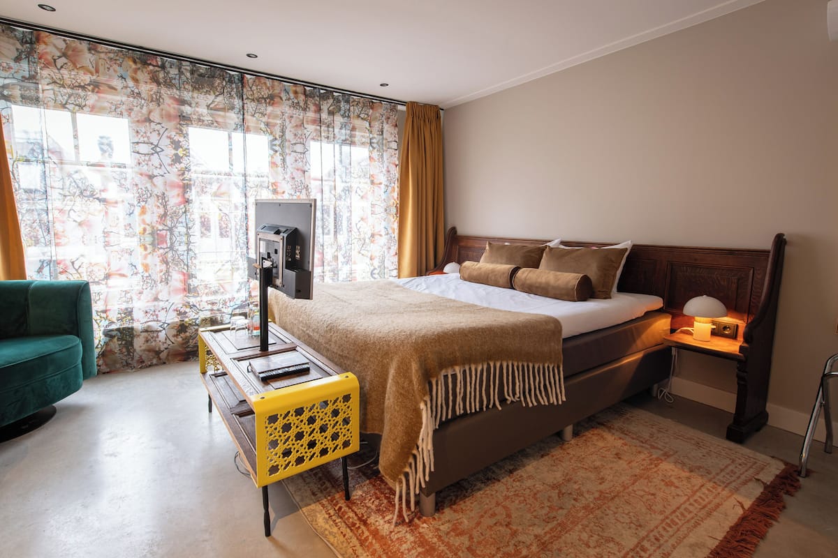 A hotel room with a bed, a desk, a chair, and a television.