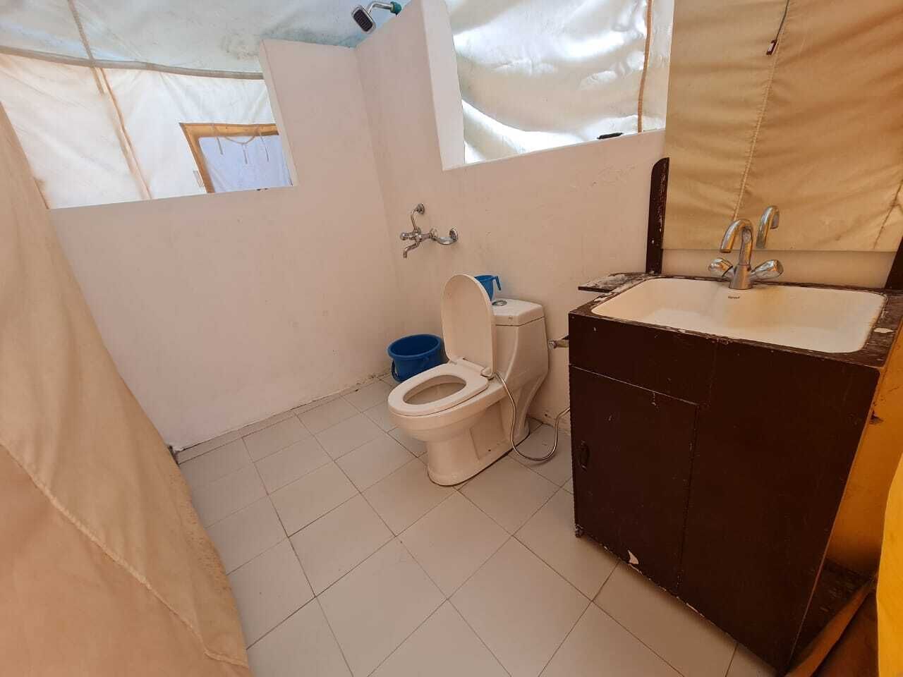 Une petite salle de bain compacte, équipée de toilettes, d’un lavabo et d’une fenêtre.