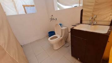 Une petite salle de bain compacte, équipée de toilettes, d’un lavabo et d’une fenêtre.