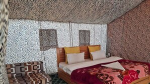Un dormitorio con una cama, una mesita de noche de madera y una silla estampada.