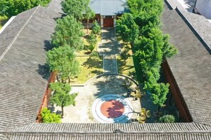 A courtyard with a central circular area, surrounded by trees and a building with a tiled roof. - Yuzhong Baguo Hotel (Langzhong)