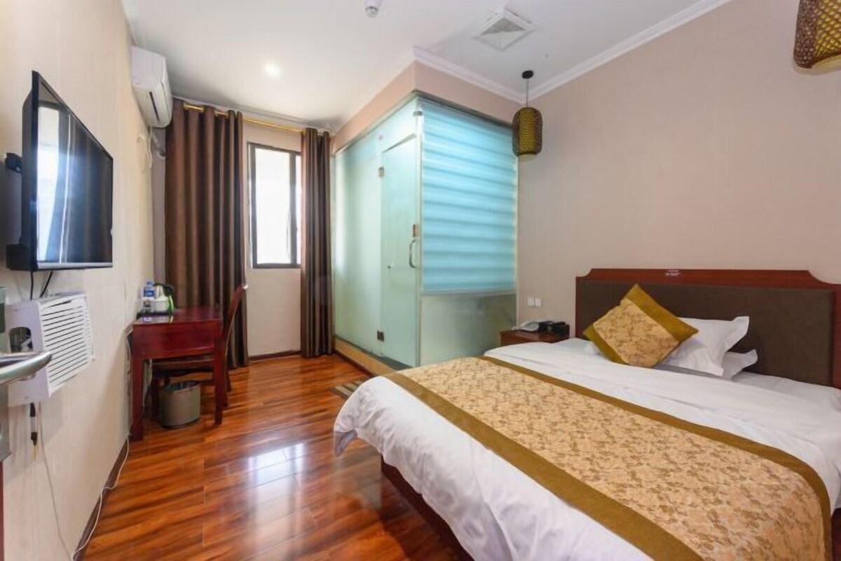 A hotel room with a bed, a TV, a desk, and a wardrobe.