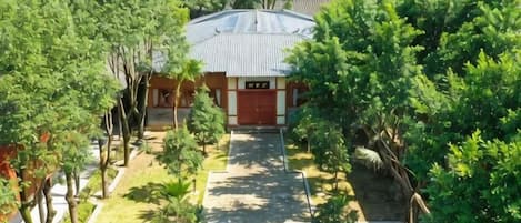 A building with a red roof, surrounded by trees and a paved walkway.
