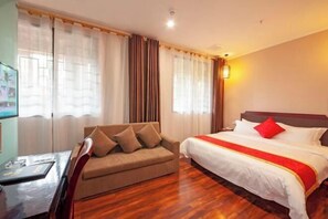 A hotel room with a bed, a sofa, a desk, and curtains. - Yuzhong Baguo Hotel (Langzhong)