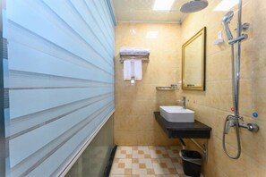 A bathroom with a tiled floor, a sink, a mirror, and a shower. - Yuzhong Baguo Hotel (Langzhong)