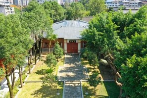 A building with a red roof, surrounded by trees and a paved pathway. - Yuzhong Baguo Hotel (Langzhong)
