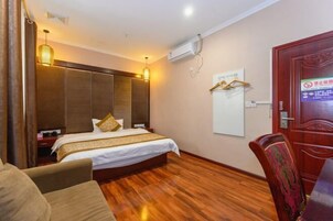 Habitación de hotel con una cama grande, piso de madera, un escritorio con silla y un armario.
