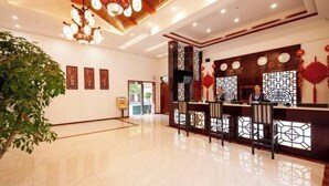 A spacious lobby with a reception desk, a large plant, and traditional decor.