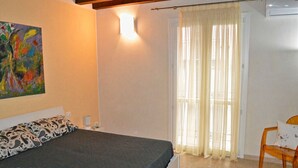 A bedroom with a bed, a chair, a painting, and a window with curtains. - House IN HISTORIC CENTER with two double rooms ba (Castellammare del Golfo)