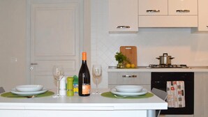 A kitchen with a dining table set for two, featuring a bottle of wine, glasses, and plates. - House IN HISTORIC CENTER with two double rooms ba (Castellammare del Golfo)