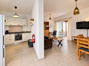 Un apartamento moderno con kitchenette, comedor, sala de estar y televisor montado en la pared.