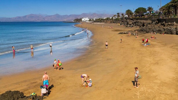 Une plage où des gens se prélassent au soleil et se promènent le long du rivage.