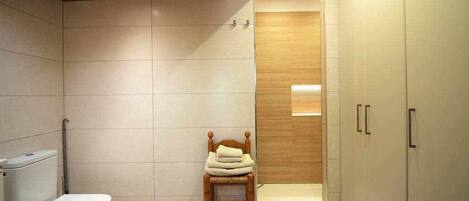 A modern bathroom with a toilet, a wooden ladder, and a shower area.