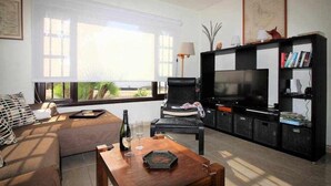 Un salon avec un canapé, une table basse, un téléviseur et une bibliothèque.