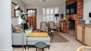 Een woonkamer met een bank, fauteuil, salontafel en open haard.