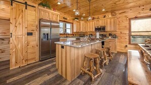 Une cuisine de style rustique, avec des éléments en bois, un îlot central, des tabourets de bar et des appareils électroménagers intégrés.