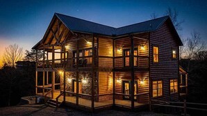 Une cabane en rondins à plusieurs étages, dotée d’un balcon à l’étage supérieur et entourée d’une clôture en bois.