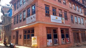 Un edificio de ladrillo de varios pisos con letreros que indican 'Luniva Restaurant & Guest House' y 'Barista Training Institute'.