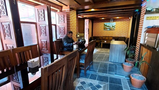 Interior de restaurante con paredes de ladrillo, muebles de madera y piso de baldosas.
