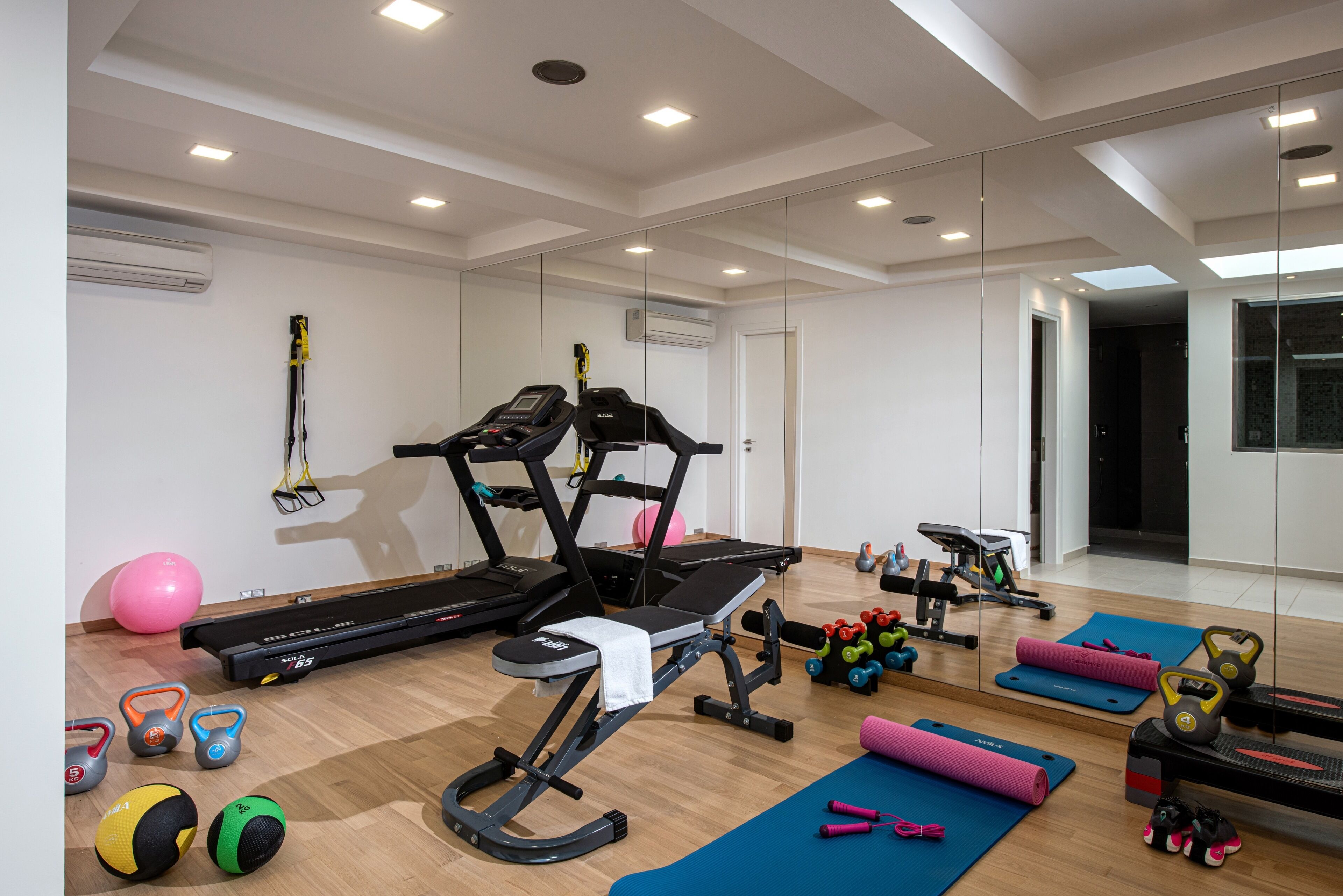Et moderne fitnesscenter med løbebånd, vægte og træningsmåtter.