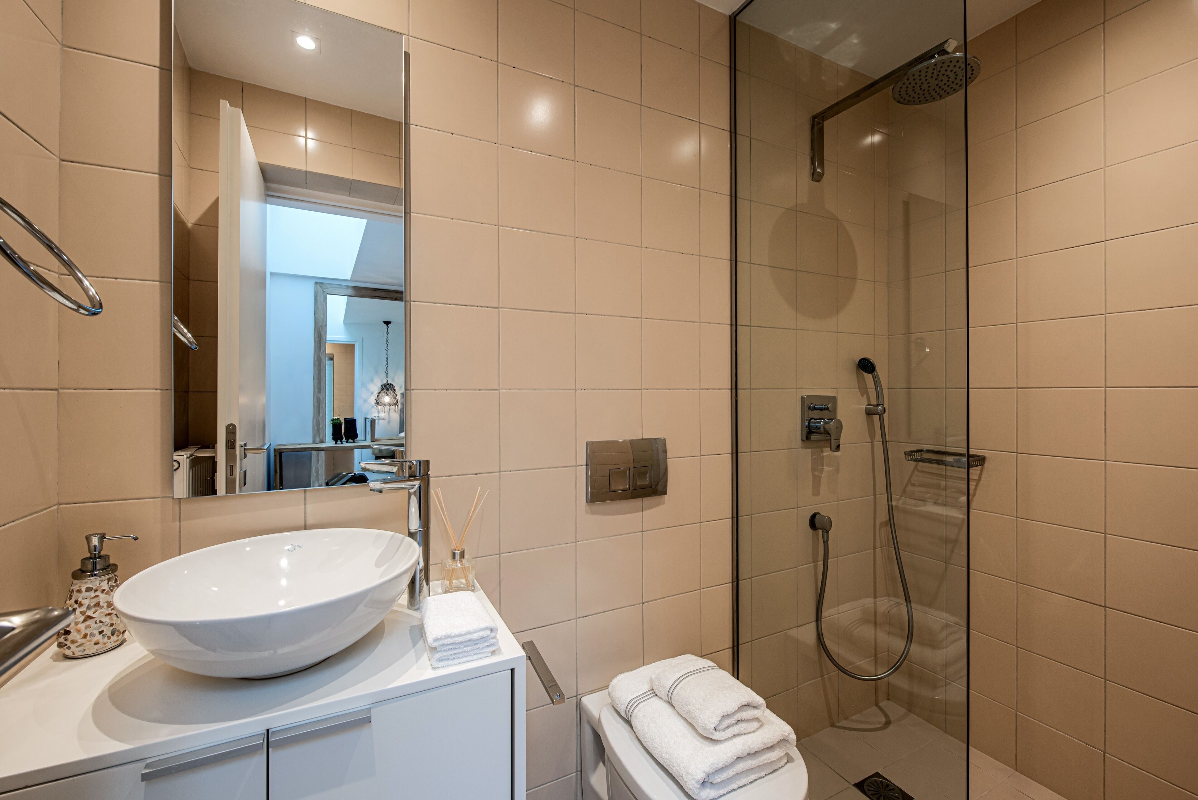 Une salle de bain moderne avec un grand lavabo blanc, une douche à parois de verre et un miroir au-dessus du lavabo.