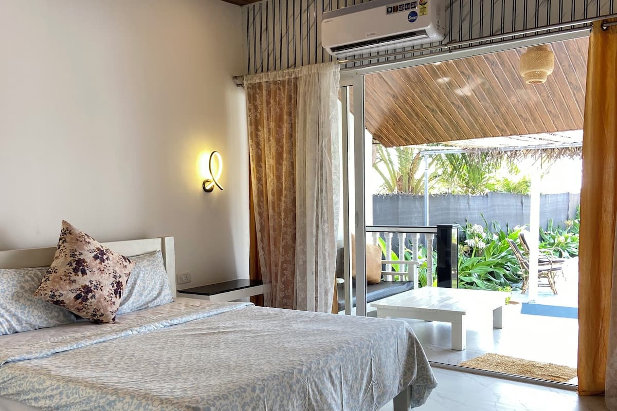 A bedroom with a bed, a ceiling fan, an air conditioning unit, and a view of the outside.