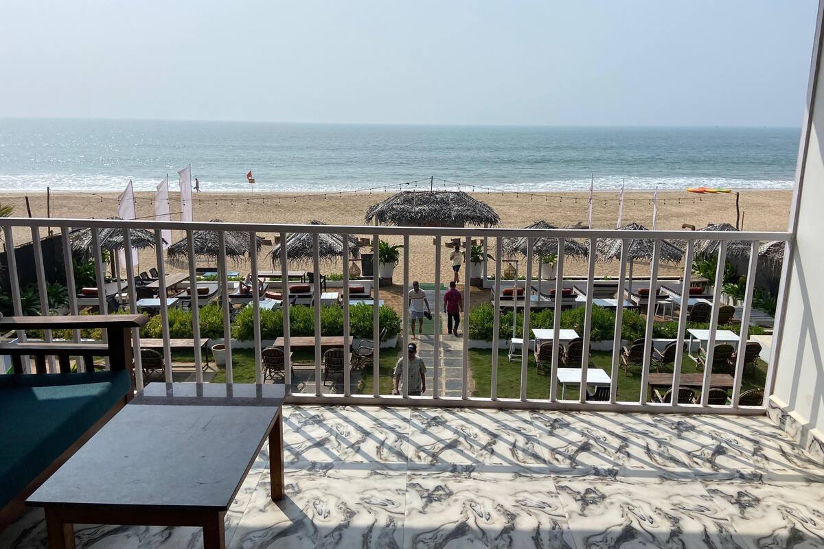 A terrace with a view of the beach, featuring outdoor seating and umbrellas.