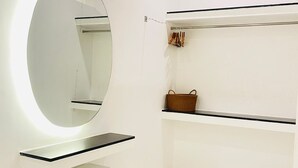 Une salle de bain moderne avec un grand miroir rond, un meuble-lavabo blanc, des pieds en bois et un revêtement de sol en marbre.