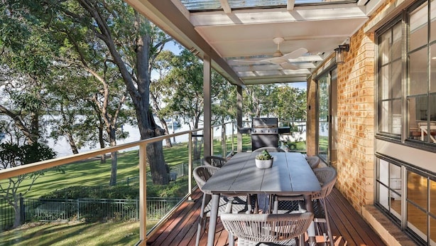 A covered outdoor patio with a table and chairs, a grill, and a view of a lake. - Kullaroo Lakehouse - Waterfront Reserve (Summerland Point)