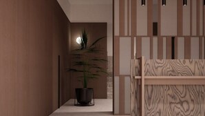 A modern interior with a wooden reception desk, a potted plant, and a wall with vertical panels. - Park Heights by the Warren Collection (Msida)