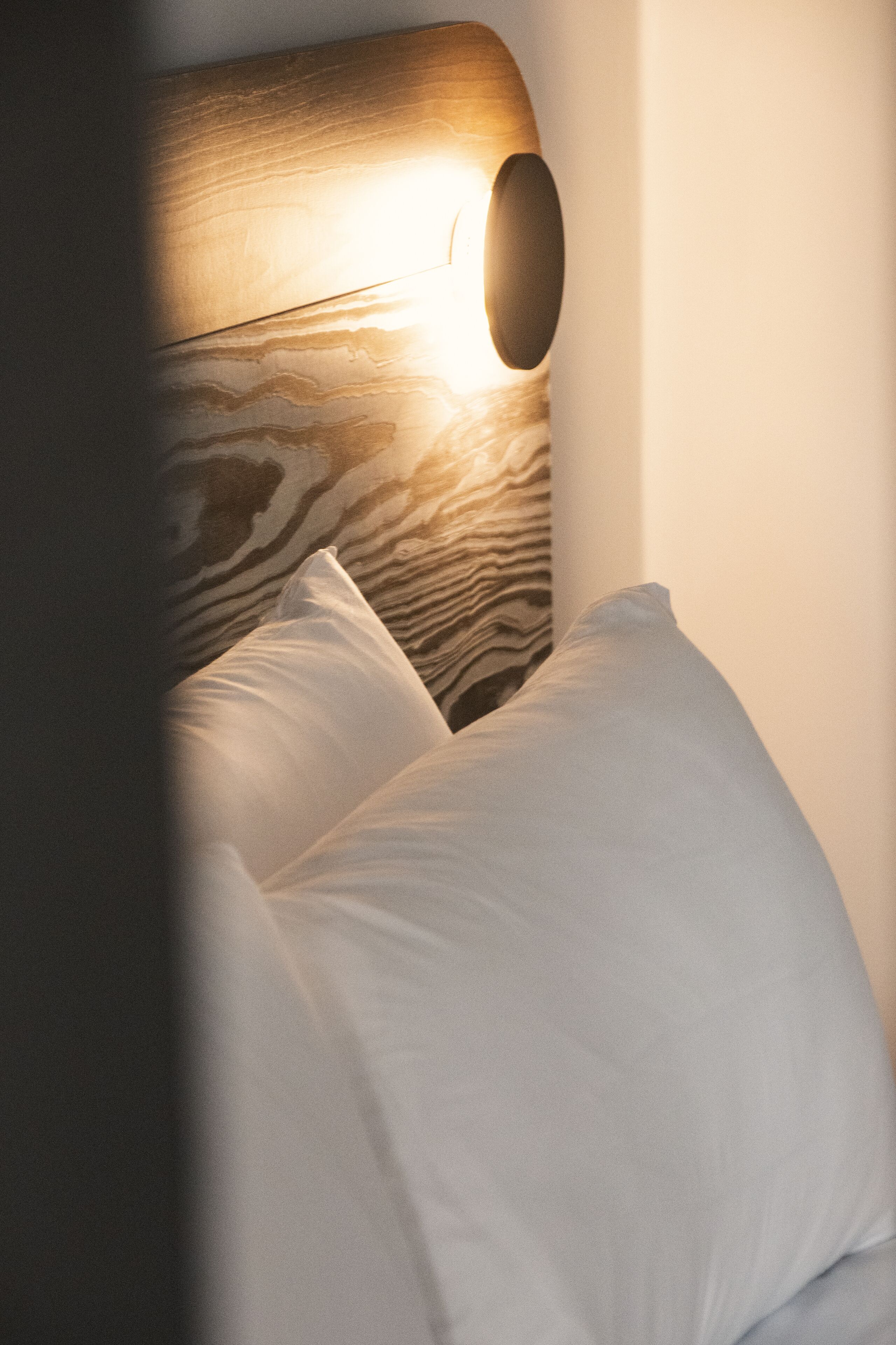 A bed with a wooden headboard and a white pillow.