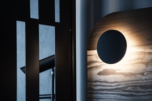 A modern interior with a wooden wall featuring a circular cut-out and a metallic structure with vertical lines. - Park Heights by the Warren Collection (Msida)
